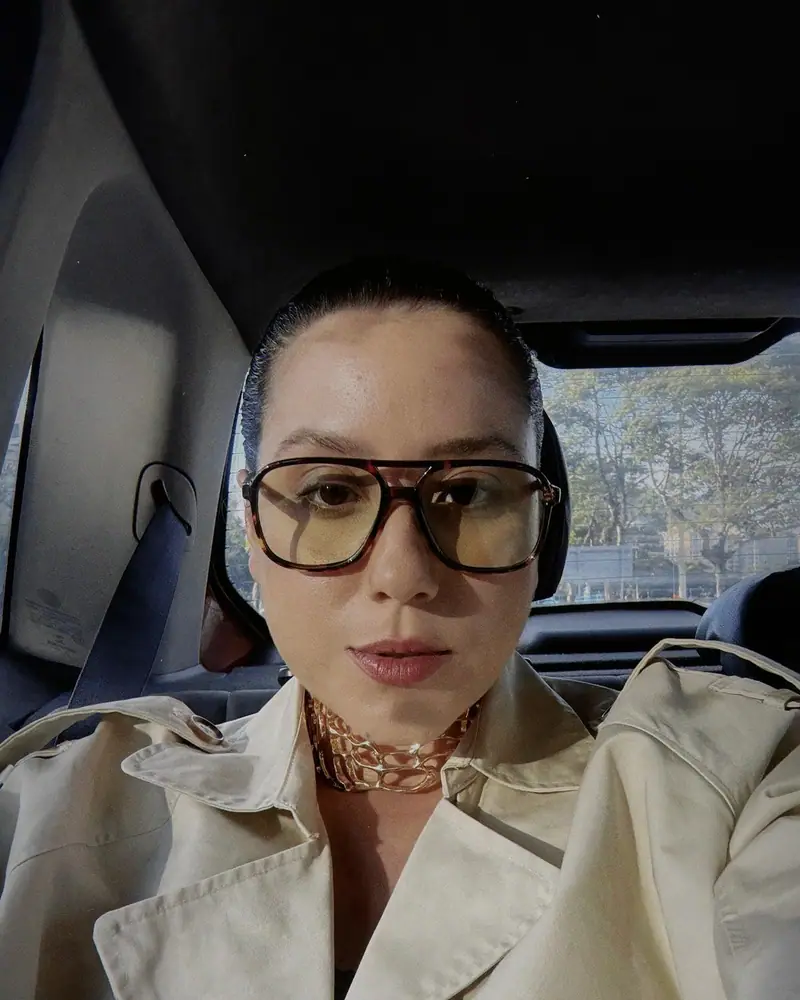 Amanda Muniz, mentora de consultoras de estilo, numa selfie de trench e óculos